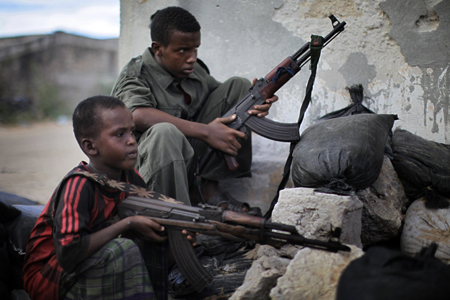 © Ed Ou / Reportage by Getty Images pour The New York Times Prix du Jeune Reporter de la ville de Perpignan 2011 #3. Mogadiscio, 24 avril 2010. Mohamed Adan Ugas (12 ans, à gauche) et Ahmed Hassan (15 ans), enrôlés dans les forces du Gouvernement fédéral de transition, montent la garde à un poste de contrôle près de l’aéroport. Ahmed déclare avoir été envoyé en Ouganda à l’âge de 12 ans pour y être formé. Il s’est fait tirer dessus par le groupe d’insurgés le plus puissant, Al-Shabab.